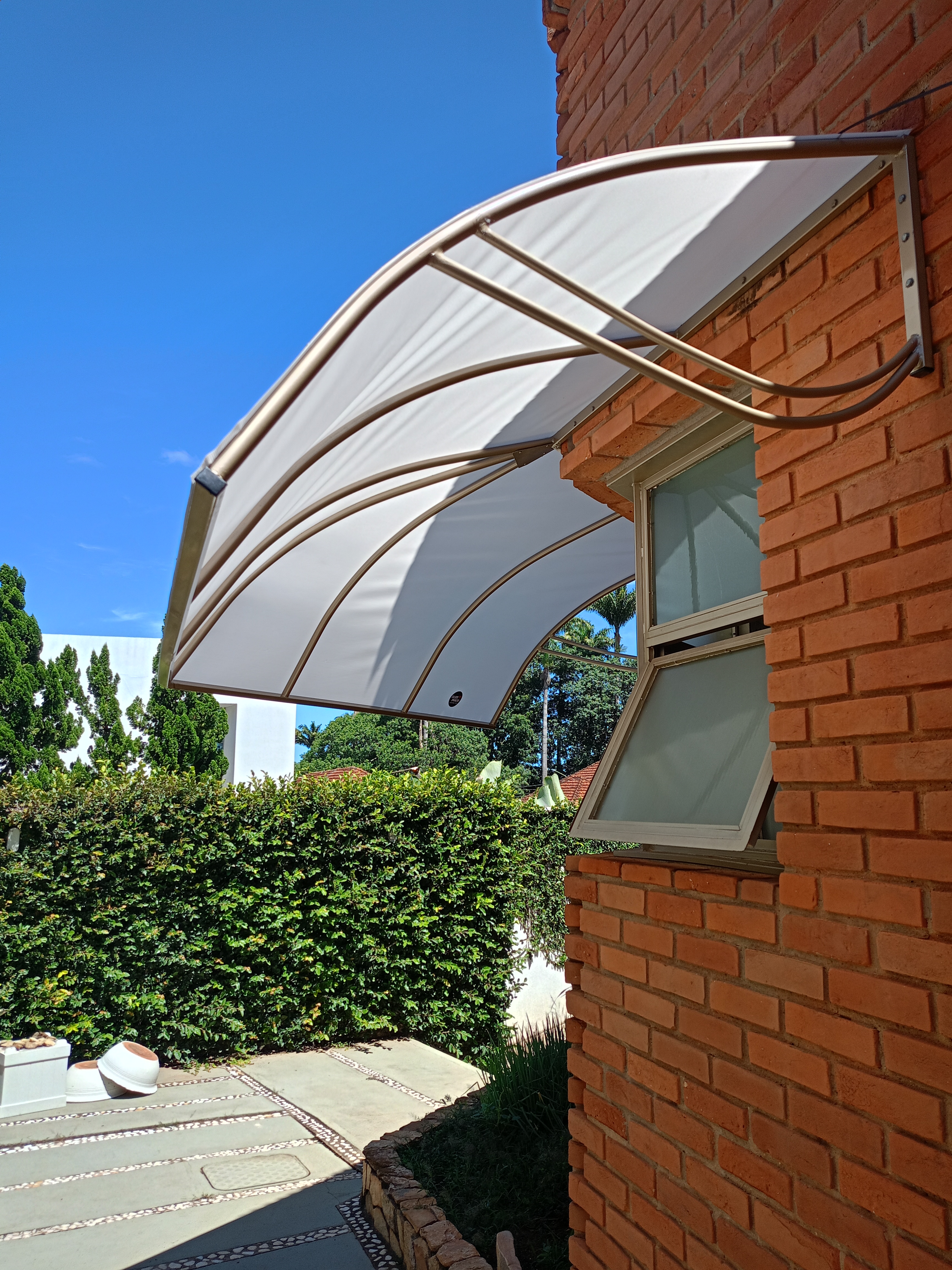 Toldo curvo branco instalado em fachada